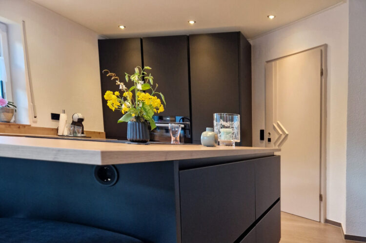 schwarze moderne Häcker Küche mit integrierten Steckdosen in der Kücheninsel